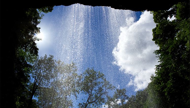 Clean water and waste managemant From the perspective of looking out from a cave, you see a thin waterfall